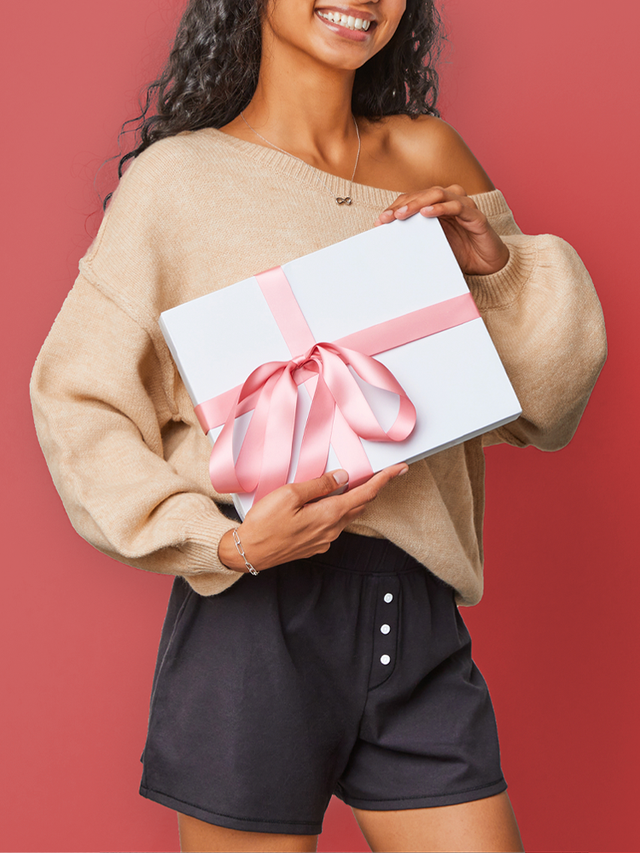 model in thinx sleep shorts holding a gift wrapped box