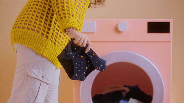 model holding period underwear in front of a washing machine