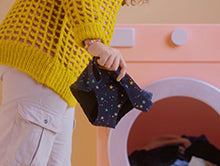 model holding teen period underwear in front of a washing machine