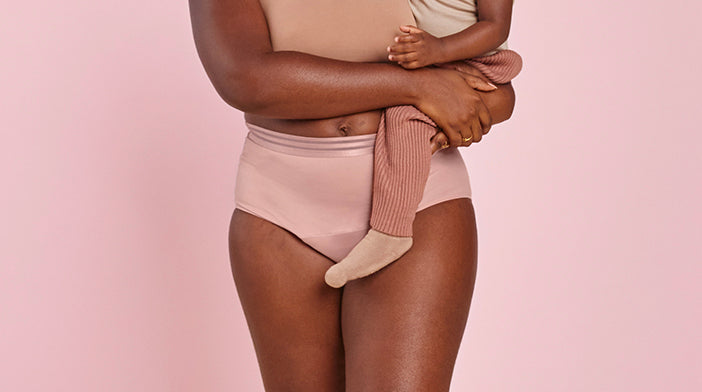 model holding a baby while wearing absorbent underwear