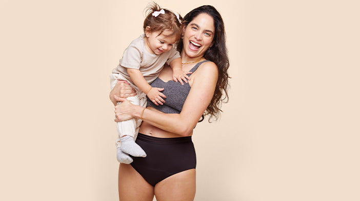 model holding a baby while wearing absorbent underwear