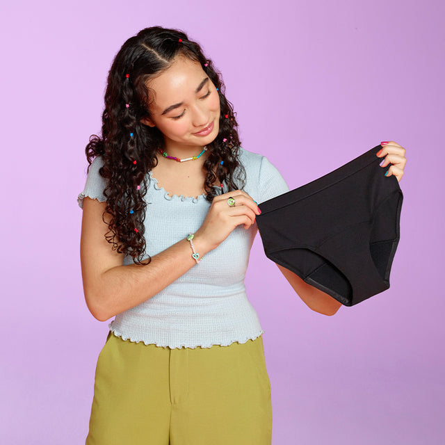 teen model holding teen period underwear in black